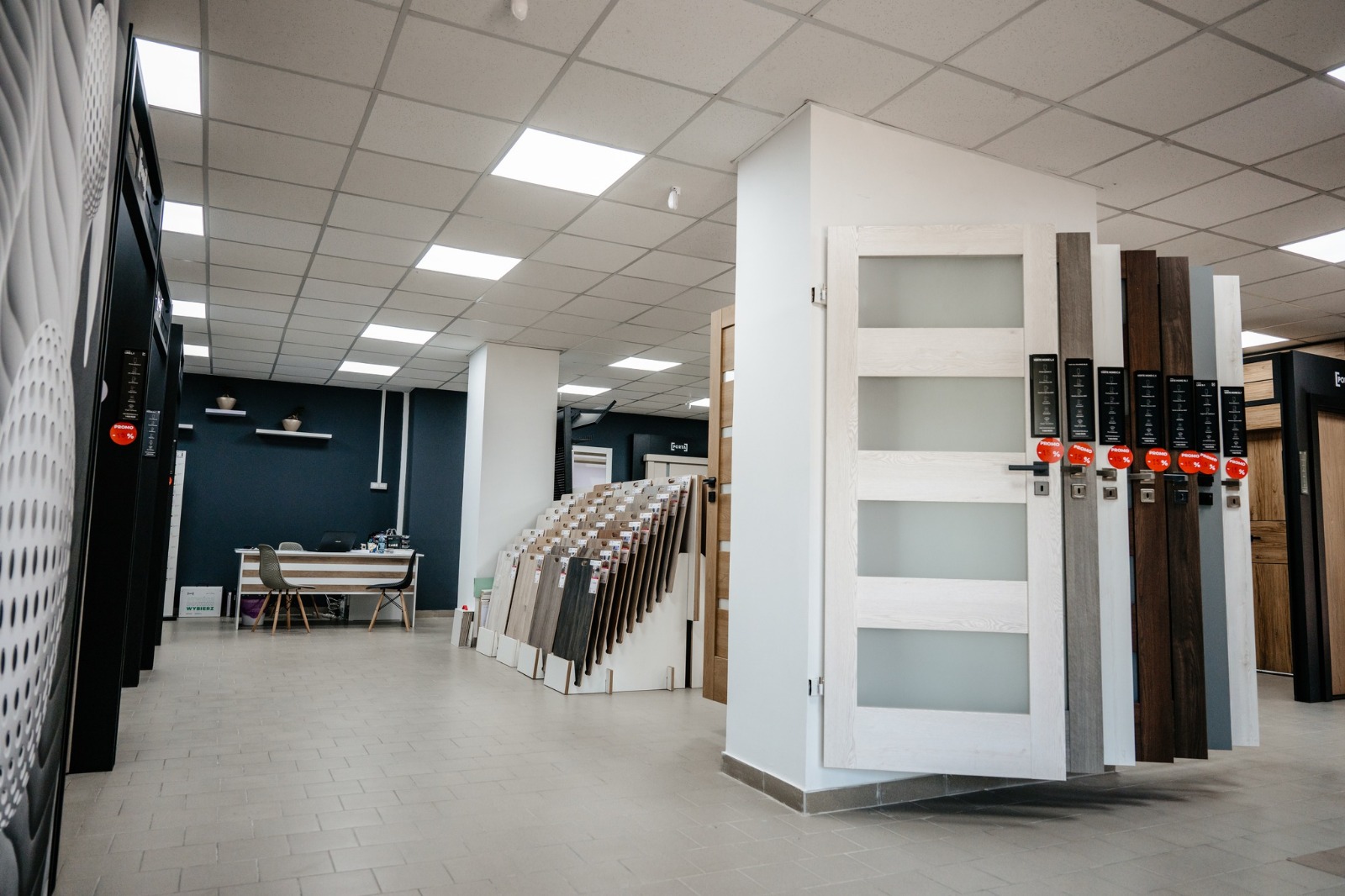 Rastelul cu foi de ușă și fâșii de finisaj din showroom-ul de uși din Bacău, fiecare cu mânerul montat pe ea
